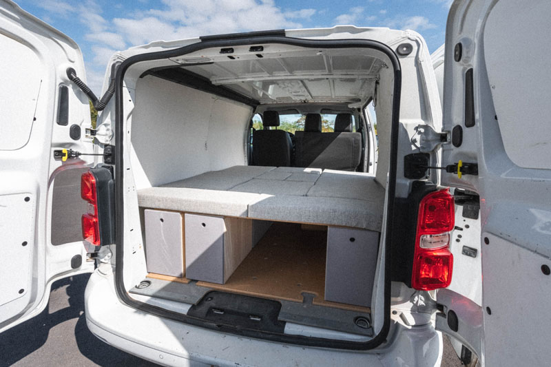 Vista interior de un Peugeot Expert camperizado con una cama instalada