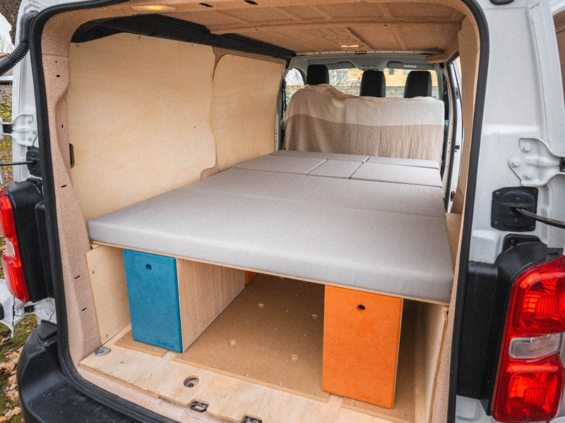 Cama en un Peugeot Expert camperizado durante un viaje